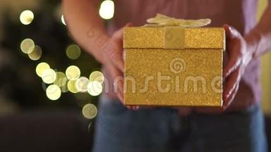 男人`手牵着一个带<strong>礼物</strong>的<strong>金色</strong>盒子，用丝带系着。 最新圣诞<strong>礼物</strong>